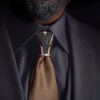 Hoodtie III - Nœud de cravate en titane noir guilloché, finition or rose, porté sur une cravate dorée